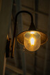 © athian - Lit vintage wall lamp with a warm yellow glow. Spiderwebs draped over the fixture add a rustic, aged charm to the dimly lit background.