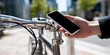 © YanabY - Person unlocking a bicycle with a smartphone in a modern urban area during daytime