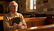 © Anna - Contemplative senior man with faith holding an old bible in church. Elderly person sitting alone in a wooden pew in prayer and devotion