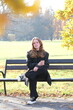 © Yevhen - Girl is sitting on a bench in city autumn park with paper cup of coffee