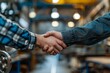 © Vorda Berge - Two adults shaking hands in a workshop showing agreement and collaboration