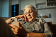 © Marko Geber - Senior woman looking concerned at smartphone at home