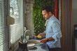 © Miljan Živković - Man washing dishes in kitchen sink with sponge