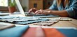 © Maryna - Interior decorator works on laptop near fabric swatches. Young woman selects colors and materials for home renovation. Creative designer plans interior design project.
