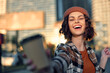 © SHOTPRIME STUDIO - Woman with smile taking a selfie in an urban street, candid and joyful portrait capturing authenticity, golden hour glow, candid lifestyle, mindful living and emotional storytelling.