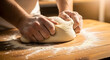 © THIBNH - Close up of baker hands kneading dough on wooden table in warm bakery light 37843907 1