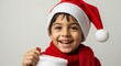 © Image - Joyful young child wearing a red santa hat and scarf, smiling brightly while holding an empty white christmas stocking against a light background