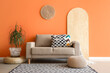 © Pixel-Shot - Comfortable sofa, poufs and houseplant in interior of living room