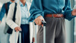 © FlexOn/peopleimages.com - Hands, people and row with suitcase at airport for travel delay, international flight and work trip. Passenger, waiting line and luggage with airplane ticket, check in and boarding for global journey