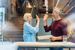 © Westend61 - Colleagues giving high five celebrating business success in modern office