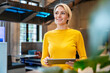 © Westend61 - Smiling professional in yellow using tablet at modern office workspace