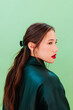 © Westend61 - Side portrait with dark green jacket on green background in studio