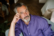 © Westend61 - Portrait of a smart mature man in a purple shirt sitting at home
