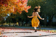© Westend61 - Woman in yellow dress jumping under autumn trees with fallen leaves