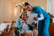 © Westend61 - Nurse assisting elderly woman in wheelchair with tablet at home