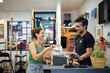 © Westend61 - Happy customer making contactless payment with smartphone in store