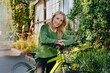© Westend61 - Woman in business wear smiling with bicycle outdoors in green urban area