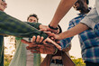 © Lomb - Diverse group of people stacking hands together outdoors showing teamwork and unity