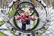 © Studio Peace - Little girl in winter clothes climbing through a metal tunnel in a snowy playground.