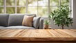 © Oleksandr - Rustic wood table with blurred cozy living space. Sunlight streams through the window accenting couch and plants. Perfect for product display or lifestyle scene.