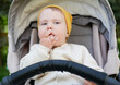 © splitov27 - Little cute baby in a hat sits in a stroller outdoors
