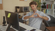 © Krakenimages.com - Man at computer typing with hands forming a heart gesture in a building office workspace; warmth connection.