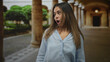 © Krakenimages.com - Woman showing open palms gesture and surprised mouth in a historic building colonnade; surprise curiosity wonder.