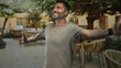 © Krakenimages.com - Man standing with arms outstretched and open palms on a restaurant terrace near a building; contentment gratitude.