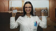 © Krakenimages.com - Woman optician in uniform holding credit card and glasses in a construction site background smiling confidently.