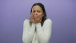 © Krakenimages.com - Young hispanic woman over isolated purple background expresses fear with hands covering face and worried expression, wearing a white sweater and showing anxiety.