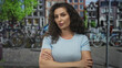© Krakenimages.com - Woman stands with arms crossed on a busy urban street in front of parked bicycles and brick buildings; confidence empowerment.