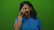 © Krakenimages.com - African american woman wearing blue shirt pinches nose with eyes closed against green studio wall; disgust.