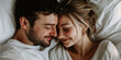 © MNStudio - Young loving couple cuddling in bed in the morning. Young man and woman hugging laying on white sheets. Husband and wife in love.
