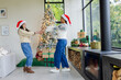© Wavebreak Media - Diverse mother and daughter wearing Santa hats spinning by Christmas tree in living room with gifts