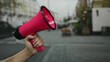 © Krakenimages.com - Man holding pink megaphone in city street signifies public announcement, showcasing hand raised with blurred background indicating urban action and spontaneous speech.