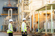 © Nutchapong Wuttisak - Male and female engineers wearing reflective vests, blueprints, toolboxes inspect the new power plant, ensuring it generates sustainable energy efficiently for global export markets.