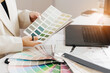 © Parilov - Female designer choosing color swatches in modern office for creative project with notebook