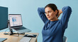 © mommy - Young woman stretches at her desk with a laptop and computer monitor