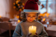 © Halfpoint - Small girl with santas hat during Christmas, holding candle.