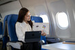 © Apichat - Businesswoman conducting online presentation during airplane travel