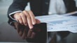 © tippapatt - Business analyst using digital tablet analyzing financial statement, business report for audit internal control system. Businesswoman working with business documents at office.