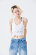 © Bangkok Click Studio - Asian confident beautiful young woman blonde hair high tied  standing wearing sleeveless top jeans on white background studio portrait lifestyle fashion street outfit trendy style pose look at camera.