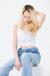 © Bangkok Click Studio - Asian confident beautiful attractive woman blonde long hair sit on cube box wear sleeveless top jeans on white background studio, portrait lifestyle fashion street outfit trendy style look at camera.