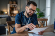 © Migma_Agency - Male nurse reviewing medical documents during home visit