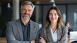 © Chumnan - Professional Pair in Office Setting: A poised man and woman, both dressed in professional attire, exude confidence and approachability, poised in a modern office environment.