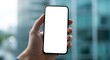 © youns - Imagen de una mano sosteniendo un teléfono móvil con pantalla blanca en el fondo natural bokeh