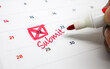 © Reza - A hand marking an urgent Submit deadline with a red pen and envelope icon on a calendar, emphasizing important due dates for tasks and projects