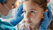 © MariКа - A healthcare professional examines a young girls eyes, showcasing compassion and care in a clinical setting