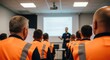 ©  zaria - Workers in high-visibility vests attending a training session in a corporate meeting room.