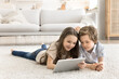 © fizkes - Portrait smiling young children lying on carpet sharing digital tablet